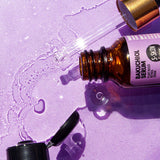 A bottle of Bakuchiol Facial Toner by S-SKIN by Snoe and a bottle of skincare water on a purple surface.