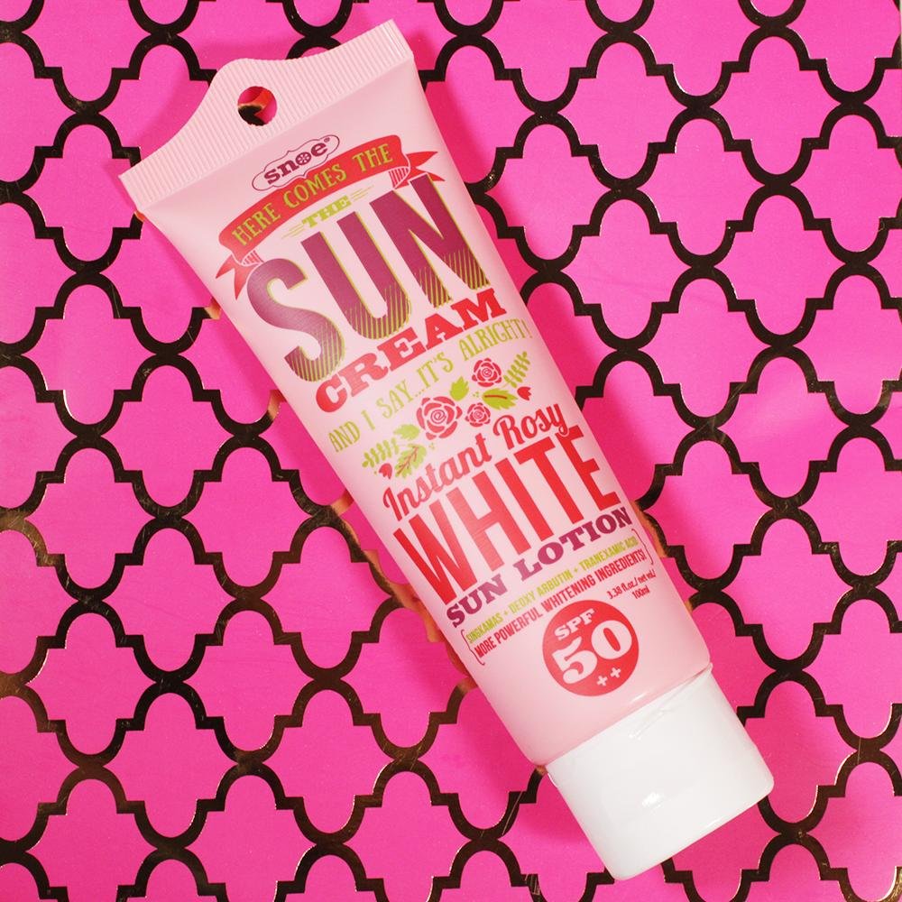 A tube of Instant Rosy White Sun Face & Body Lotion SPF 50++ from HERE COMES THE SUN CREAM on a pink background, providing skincare protection against harmful UV rays.