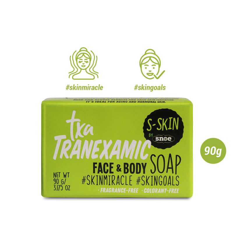 A green box of S-SKIN by Snoe's TXA Tranexamic Face and Body Soap, 90g, prominently features "fragrance-free" and "colorant-free" labels. Icons above the box highlight "#skinmiracle" and "#skingoals," making it an essential product for skin care and brightening without the need for makeup.